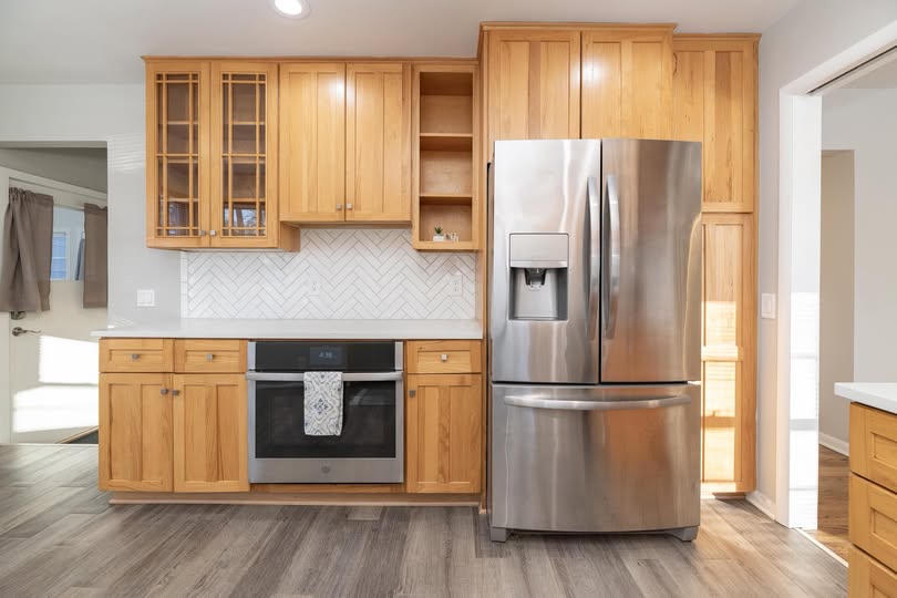 Finished kitchen with oak cabinetry, white herringbone backsplash, stainless range and French-door refrigerator