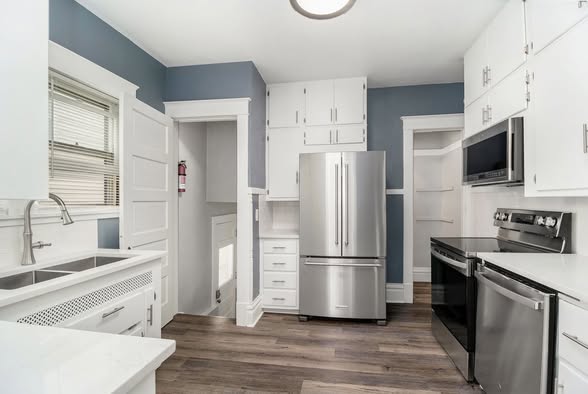 Finished kitchen with white cabinetry, blue-gray walls and stainless appliances
